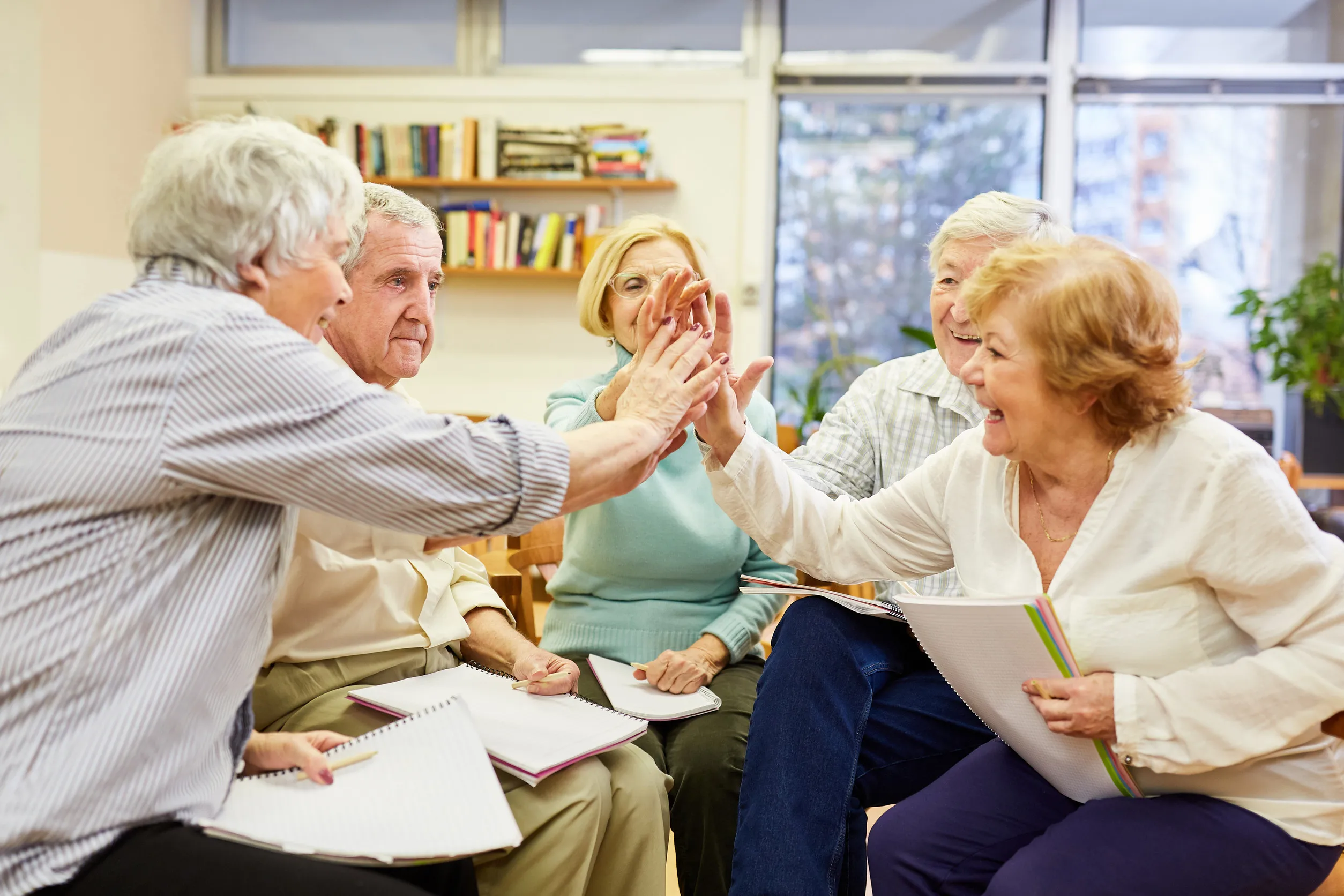 Seniors do high five in group therapy for motivation and community Seniors do high five in group therapy for motivation and community